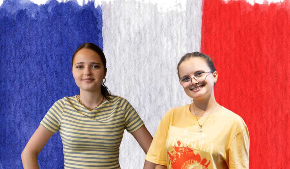 Zwei Schülerinnen vor der französischen Flagge
