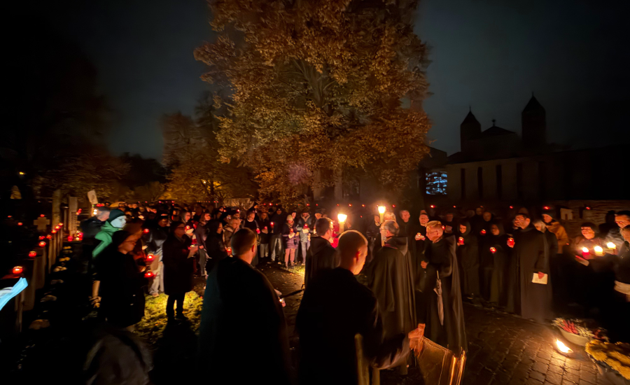 Menschen und Mönche mit vielen Lichtern auf dem dunklen Friedhof