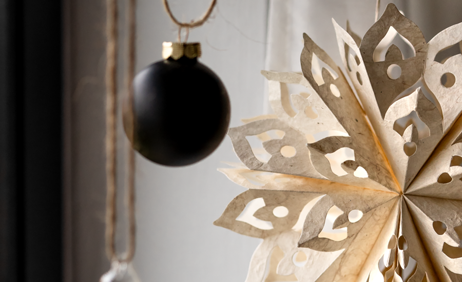 Schwarze Christbaumkugel und Papierstern