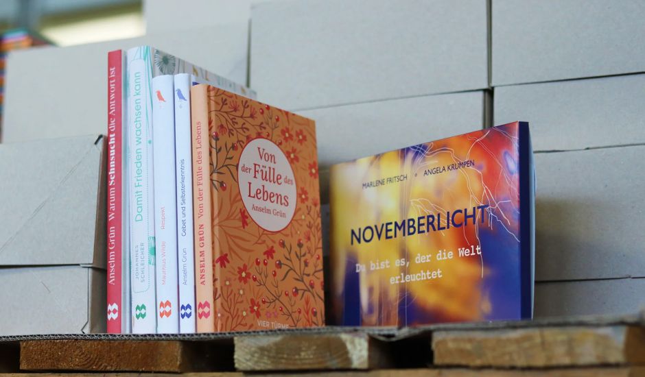 Bücherstapel steht auf einer Holzpalette vor Kartons