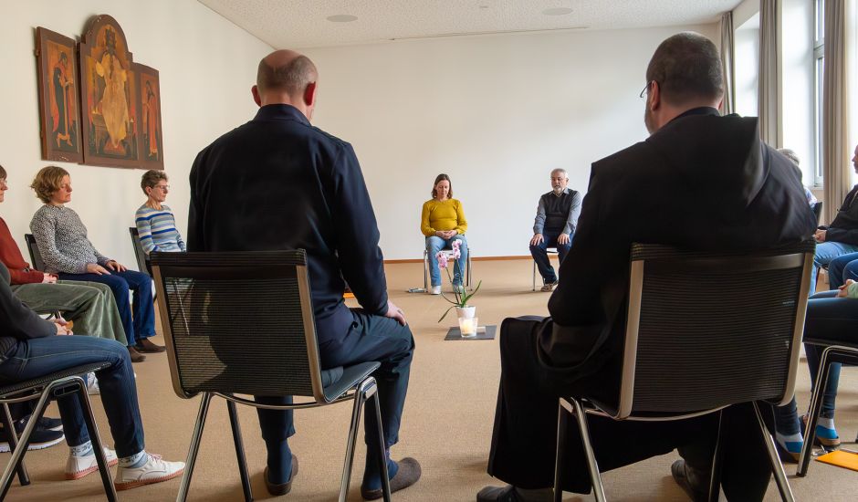 Menschen sitzen im Kreis in einem Tagungsraum