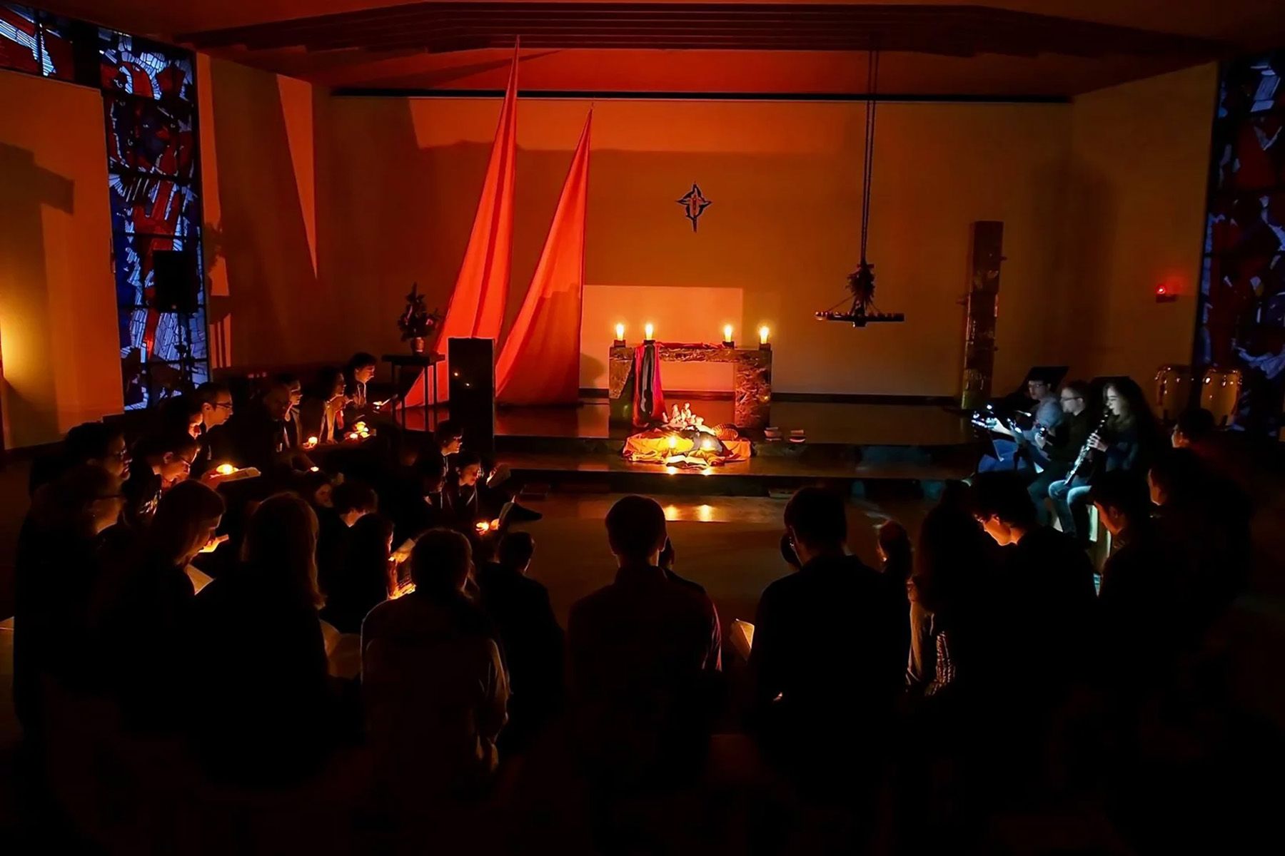 Junge Menschen feiern Andacht in einer mit Kerzen beleuchtenden Kapelle