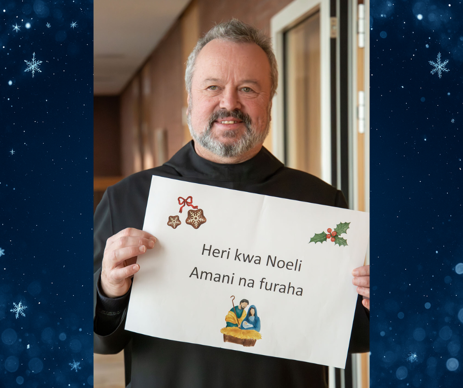 Mönch hält Schild mit Weihnachtsgrüßen hoch