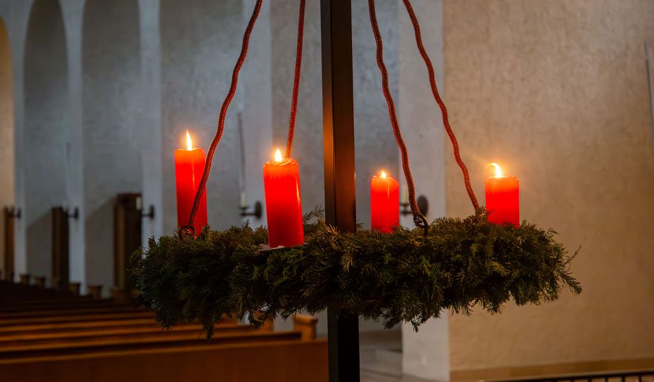 Adventskranz, bei dem vier Kerzen angezündet sind.