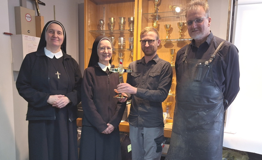 Zwei Ordensschwestern und zwei Mitarbeiter bei der Übergabe des Reliquiars