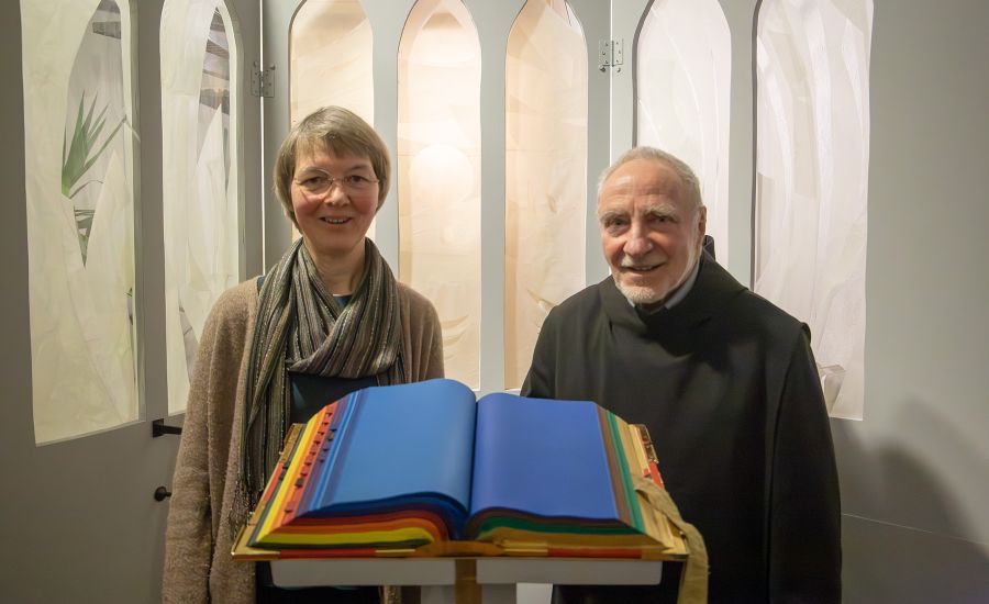 Frau und Mann stehen hinter einem bunt bemalten Buch