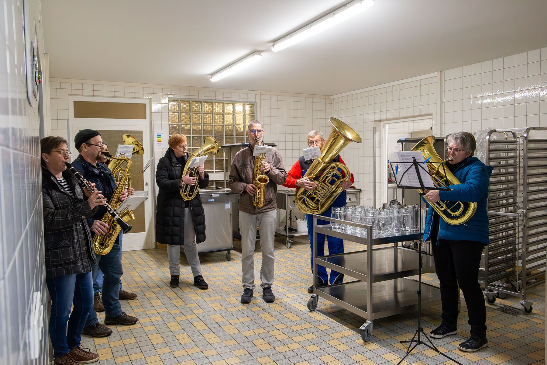 Fünf Musiker mit Blechblasinstrumenten in einer Großküche